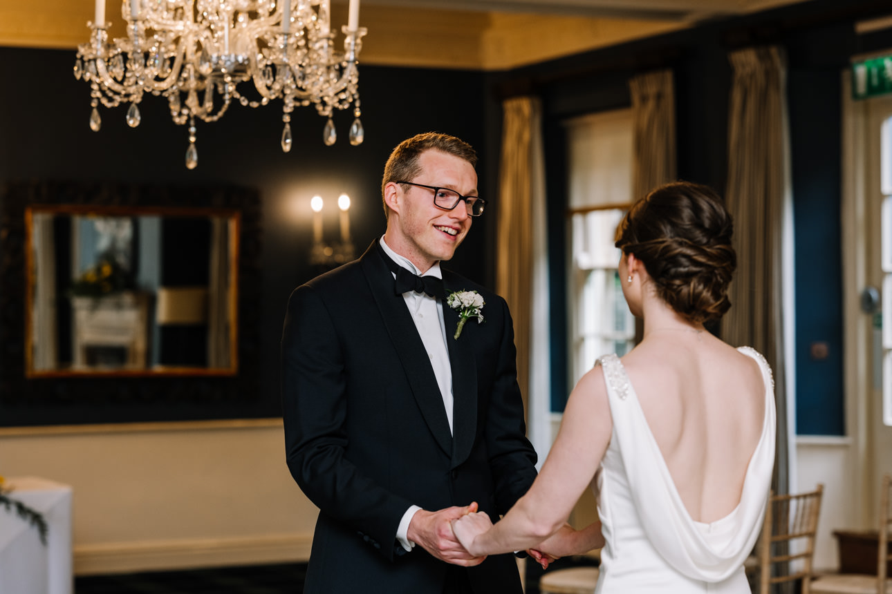 SUMMER WEDDING AT THE SWAN HOTEL BIBURY 19 Romantic candid of the groom smiling at his bride before their summer wedding at the Swan Hotel Bibury.