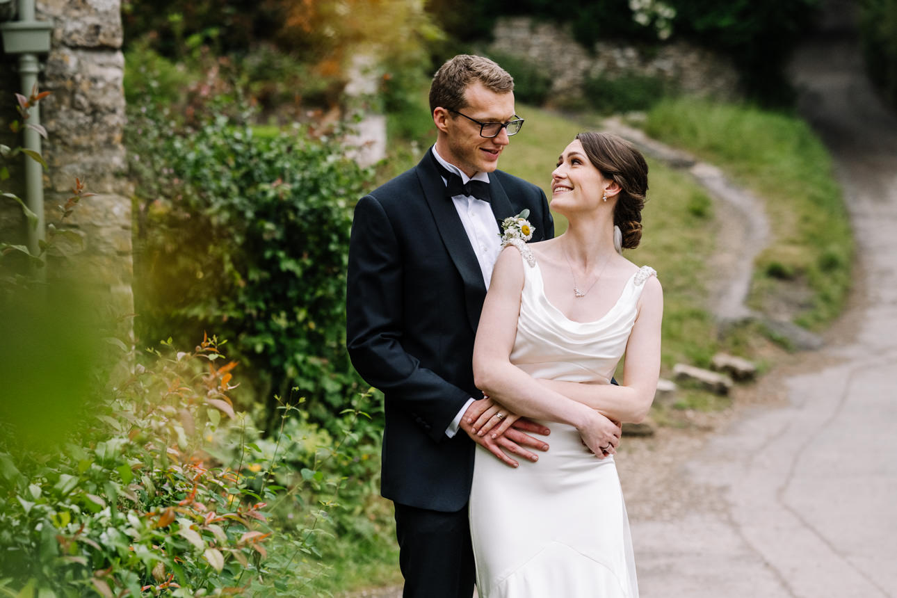 SUMMER WEDDING AT THE SWAN HOTEL BIBURY 39 Bride and groom walking hand in hand along arlington row path during their summer wedding at the Swan Hotel Bibury.