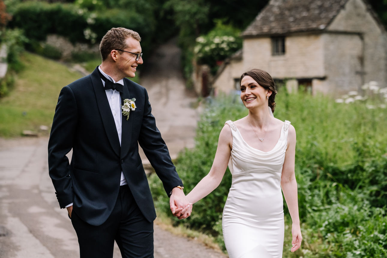 SUMMER WEDDING AT THE SWAN HOTEL BIBURY 41 Bride and groom strolling down a quaint village country lane for their summer wedding at the Swan Hotel Bibury.