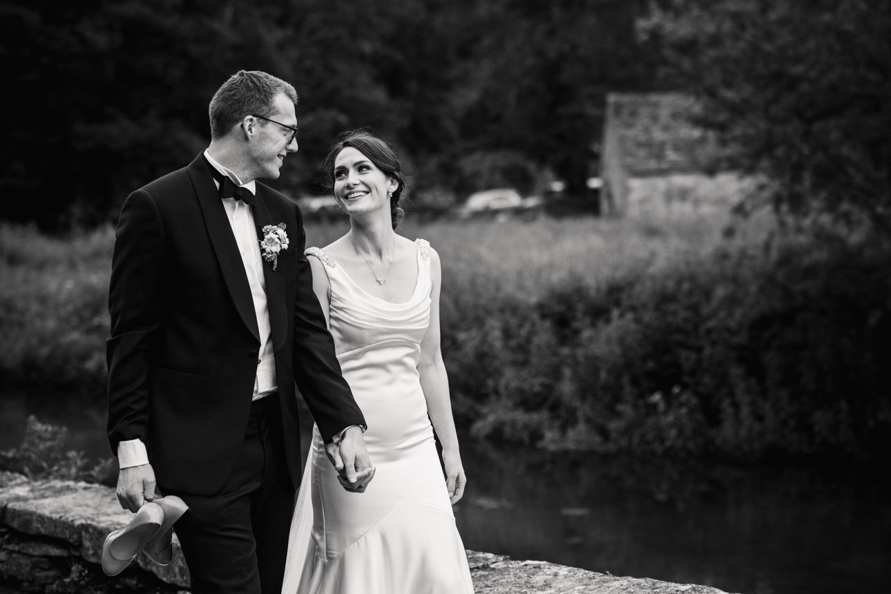 SUMMER WEDDING AT THE SWAN HOTEL BIBURY 44 Elegant black and white portrait of the couple walking through the grounds during their summer wedding at the Swan Hotel Bibury.