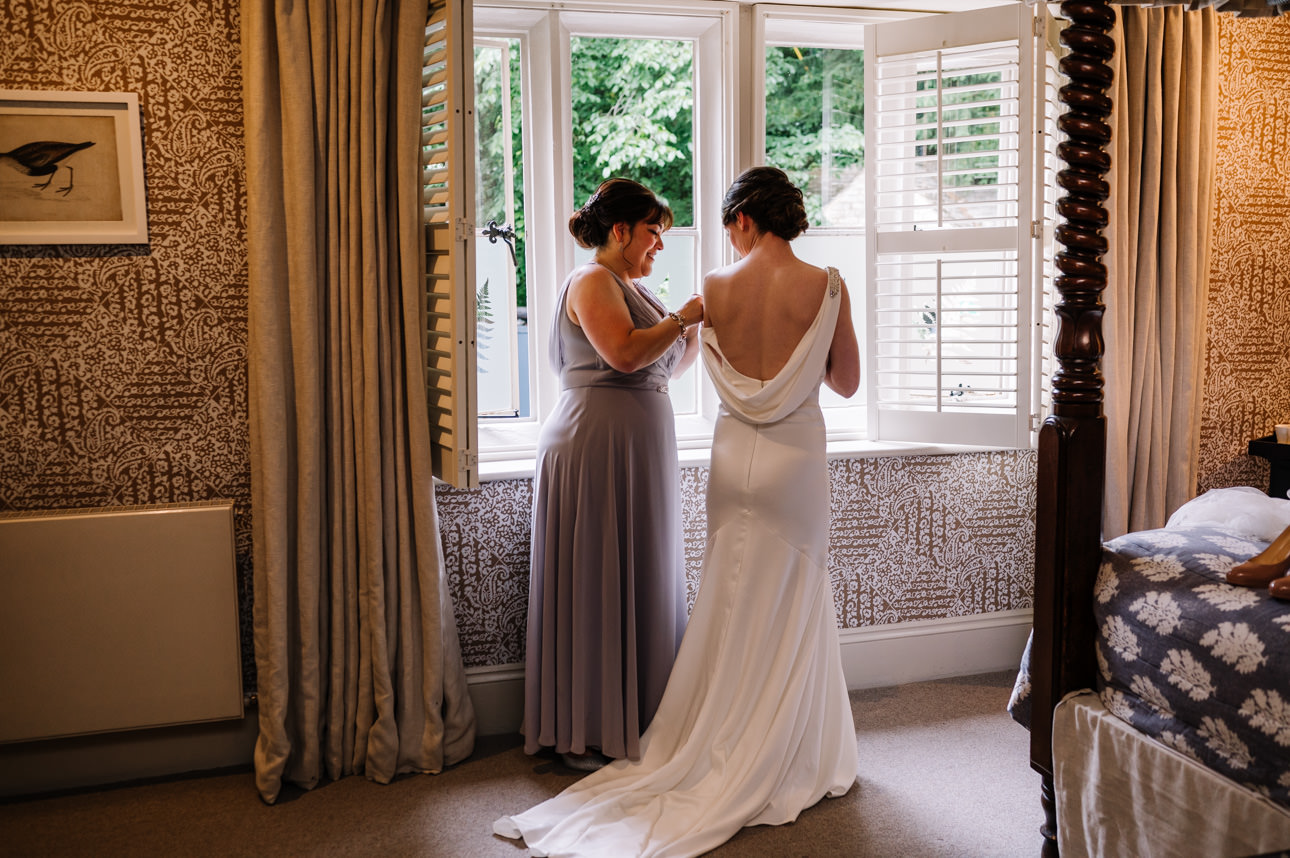 SUMMER WEDDING AT THE SWAN HOTEL BIBURY 12 Bride and bridesmaids looking out the window while getting ready for a summer wedding at the Swan Hotel Bibury.
