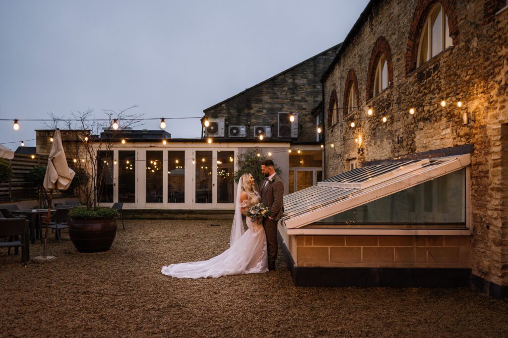 A CHRISTMAS WINTER WEDDING AT THE KINGS HEAD 31 Bride and groom standing together outside the Kings Head Hotel with the bride's train flowing behind her