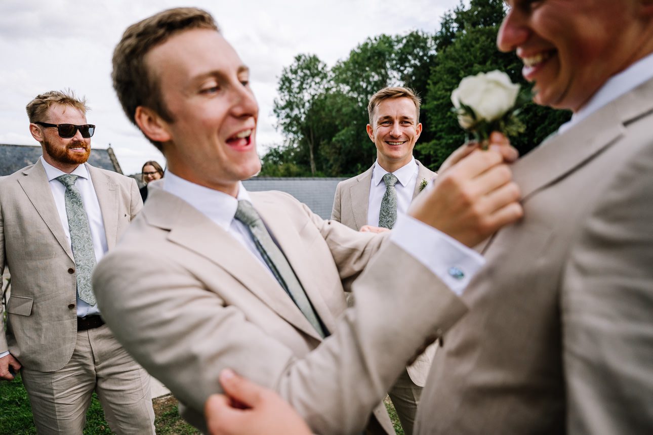 Groomsmen adjusting suits outdoors.
