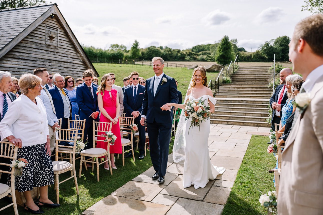 Bride arriving at the aisle for summer wedding at Upcote Barn.
