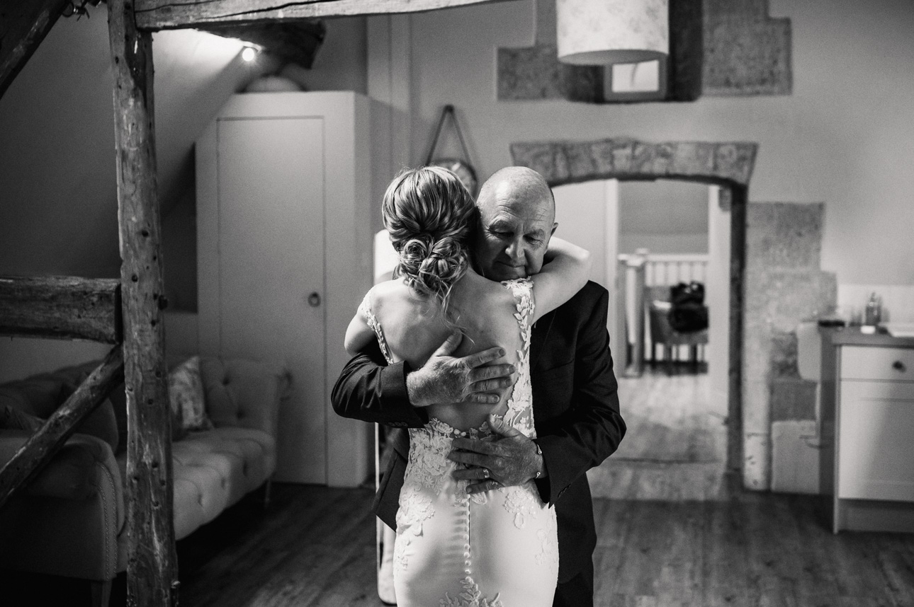 LAPSTONE BARN WEDDING PHOTOGRAPHER 24 Father of the bride hugging his daughter after the dress reveal at Lapstone Barn wedding venue.