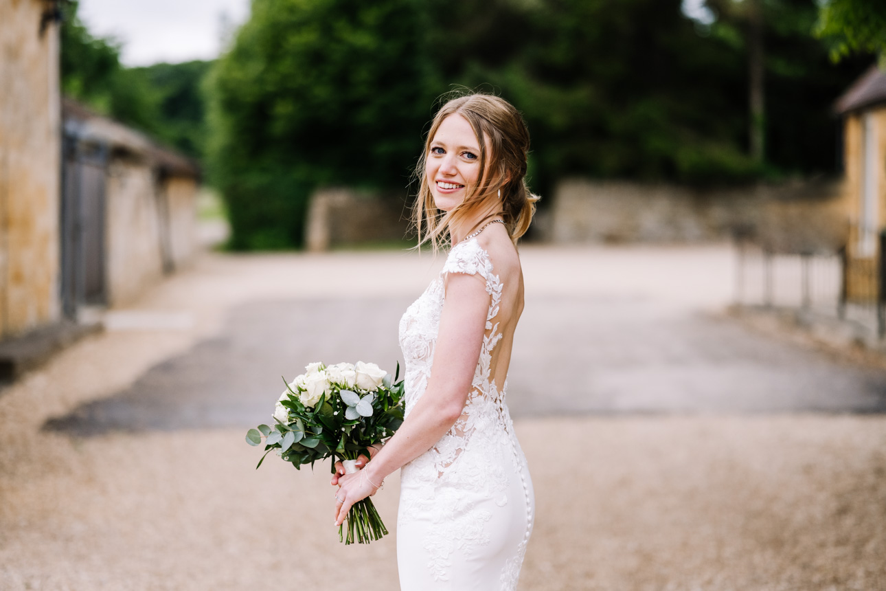 LAPSTONE BARN WEDDING PHOTOGRAPHER 54 Elegant side-profile portrait of a bride holding a white bouquet against the rustic outdoor backdrop of Lapstone Barn.