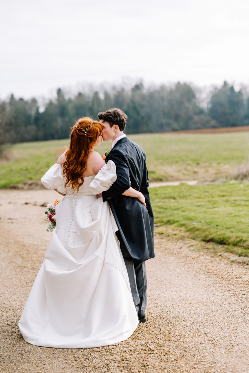 LAPSTONE BARN WEDDING PHOTOGRAPHER 58 Rear view of a bride and groom with red hair walking together down a pathway at a Lapstone Barn wedding.