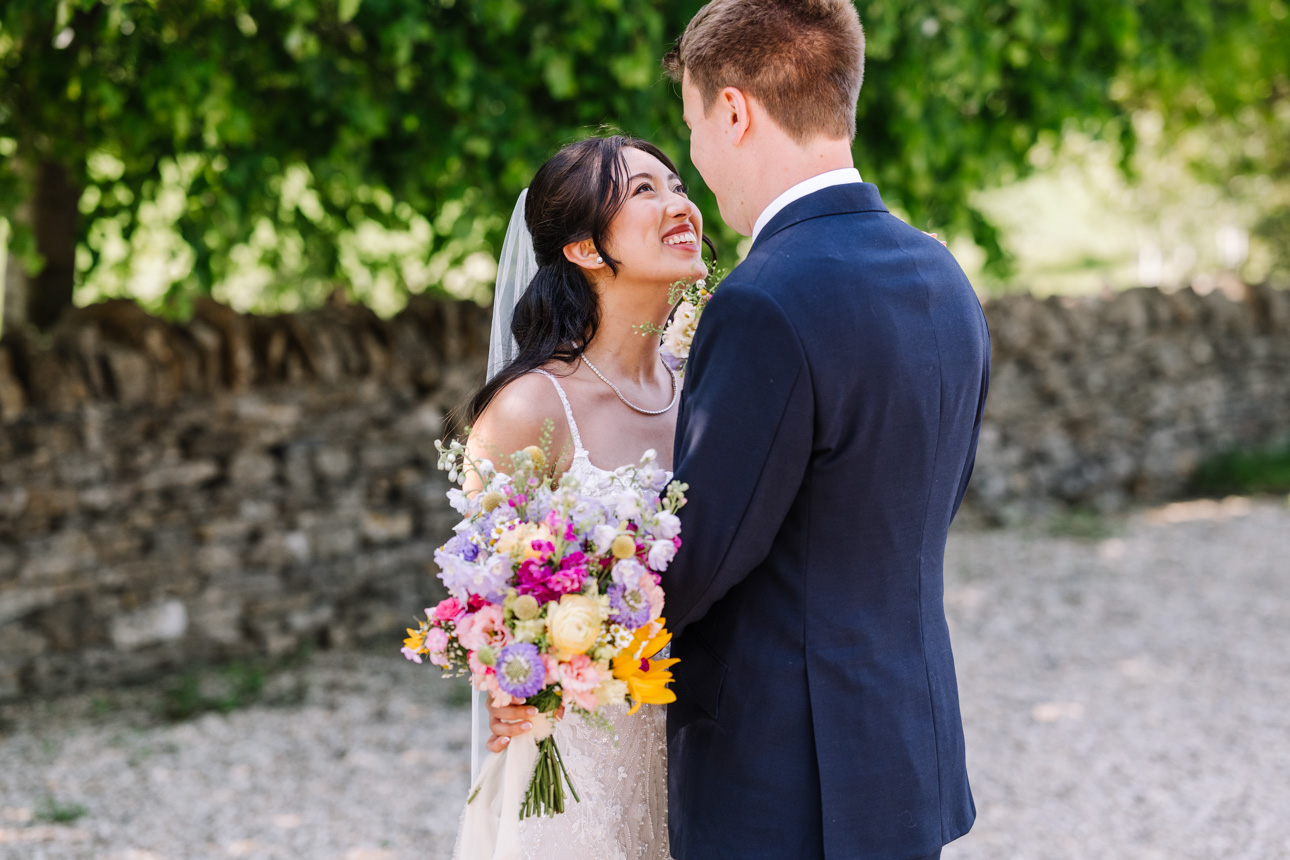 LAPSTONE BARN WEDDING PHOTOGRAPHER 41 Intimate wedding portrait of a bride holding a colorful bouquet while looking up at her groom, taken by Lapstone Barn wedding photographer Tanli Joy Weddings.