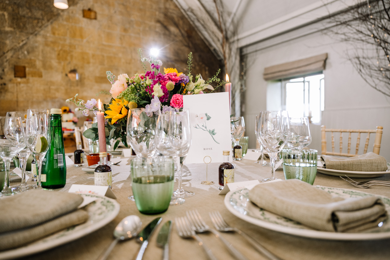 LAPSTONE BARN WEDDING PHOTOGRAPHER 77 Vibrant summer floral centerpieces on a beautifully dressed round table for a wedding breakfast at Lapstone Barn.