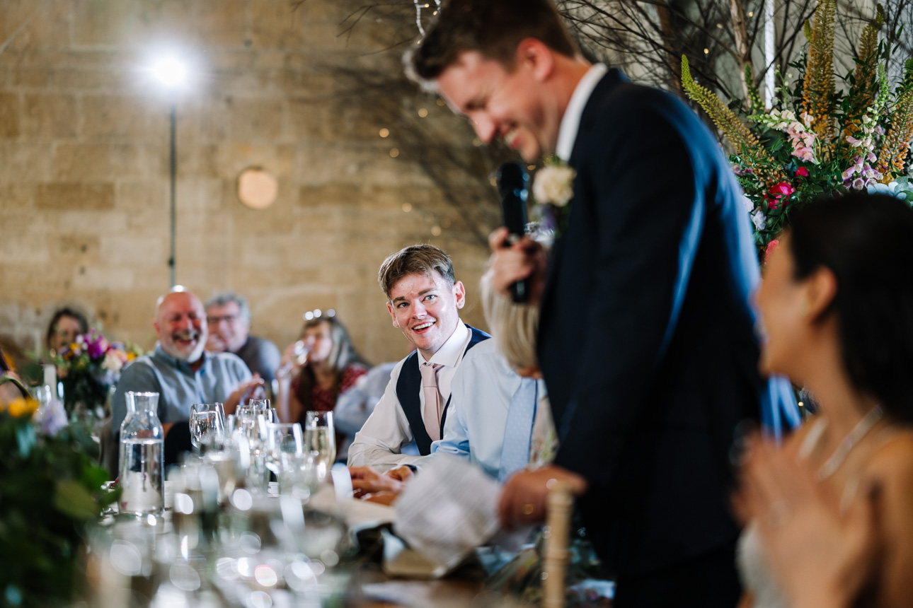 LAPSTONE BARN WEDDING PHOTOGRAPHER 80 A groom smiling and laughing during the wedding reception speeches captured by Tanli Joy Weddings at Lapstone Barn.