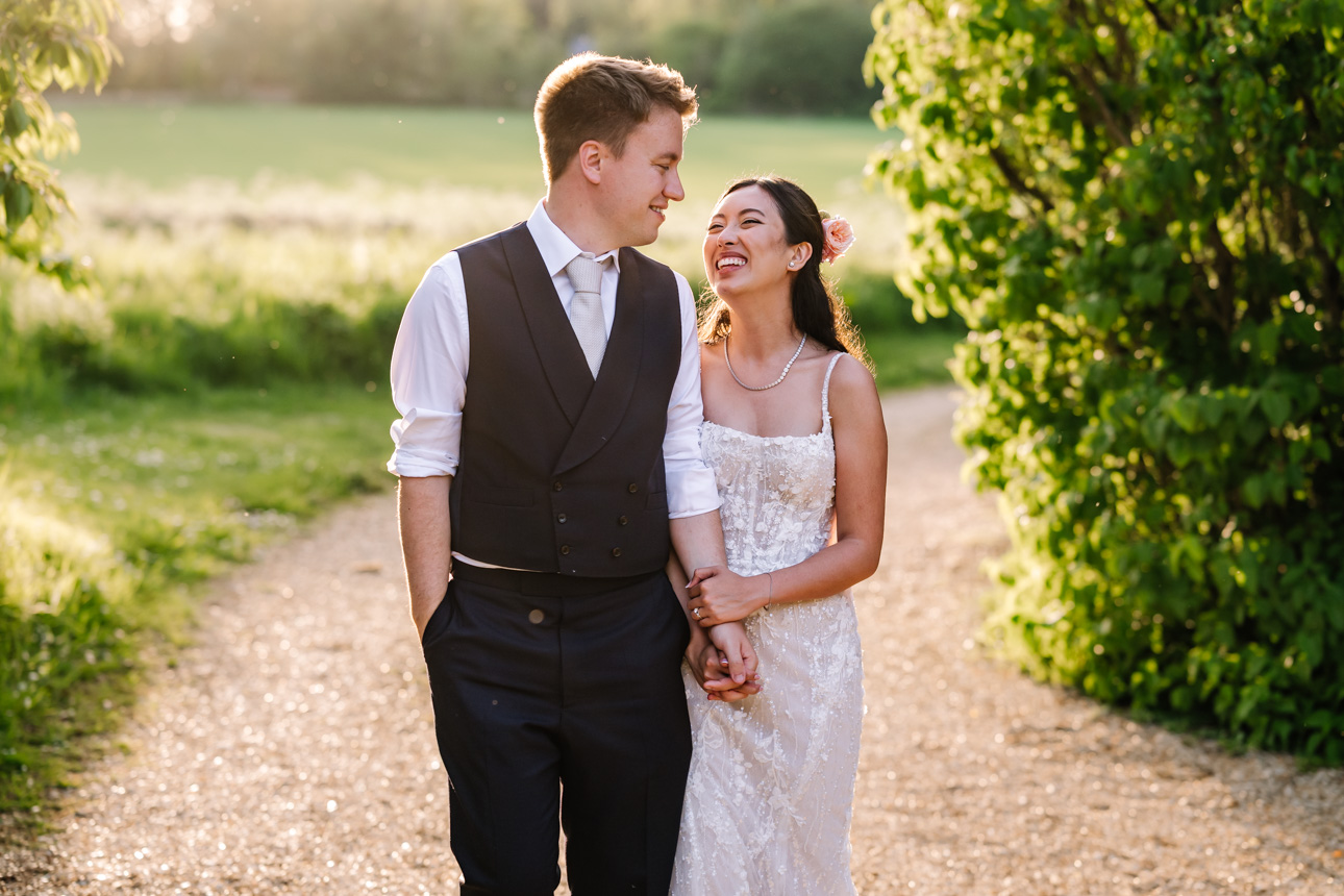 LAPSTONE BARN WEDDING PHOTOGRAPHER 47 Candid photography of a newlywed couple walking hand-in-hand down a country path at Lapstone Barn.