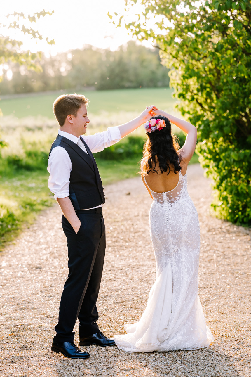 LAPSTONE BARN WEDDING PHOTOGRAPHER 71 Candid wedding photography of a newlywed couple walking through fields during a warm golden hour sunset at Lapstone Barn.