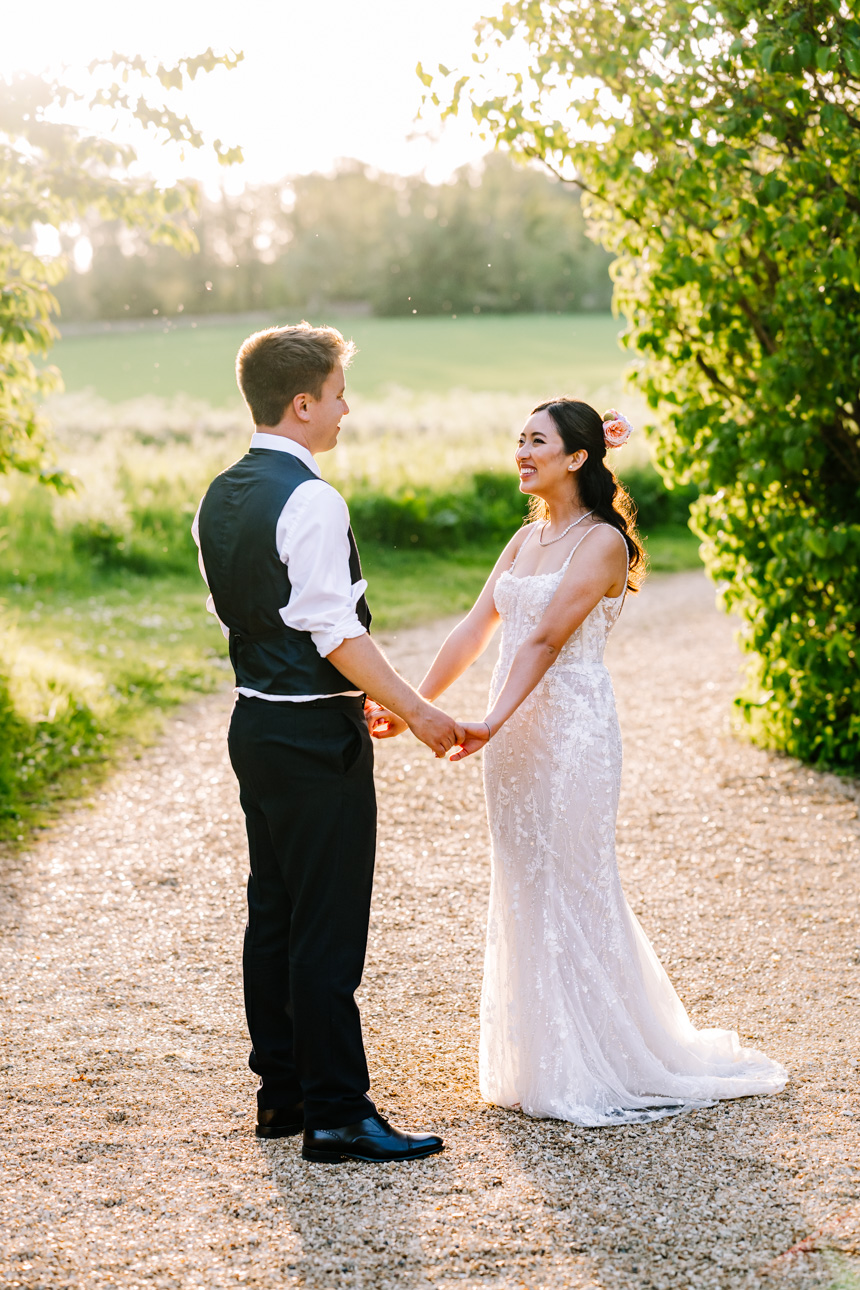 LAPSTONE BARN WEDDING PHOTOGRAPHER 72 Candid wedding photography of a newlywed couple walking through fields during a warm golden hour sunset at Lapstone Barn.