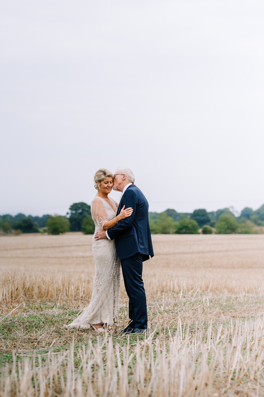 LAPSTONE BARN WEDDING PHOTOGRAPHER 62 Bride and groom posing together in an open field under a soft overcast sky, taken by Lapstone Barn wedding photographer Tanli Joy Weddings.