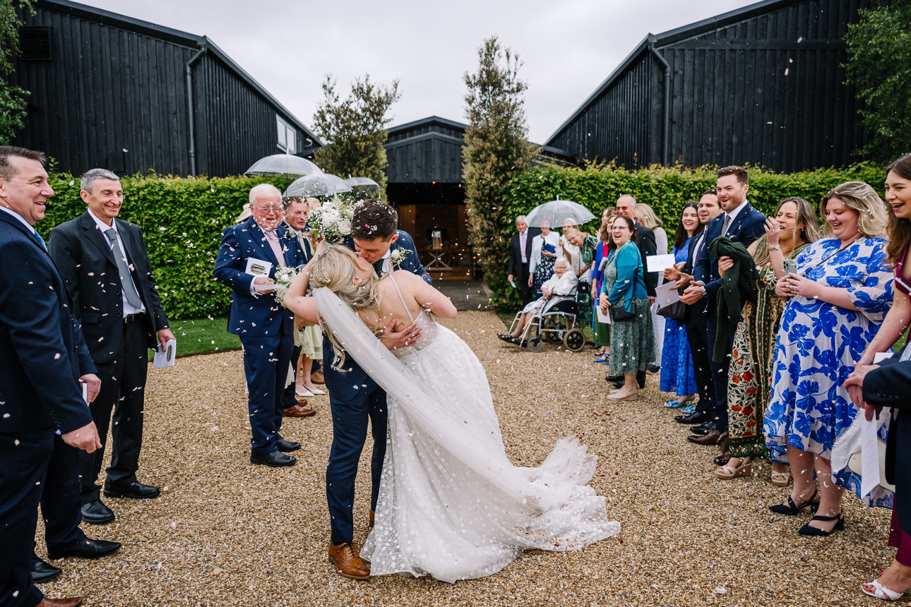 FLORA AND WILLIAM PRIMROSE HILL FARM SPRING WEDDING 36 Bride and groom celebrating with their guests during a colourful confetti exit