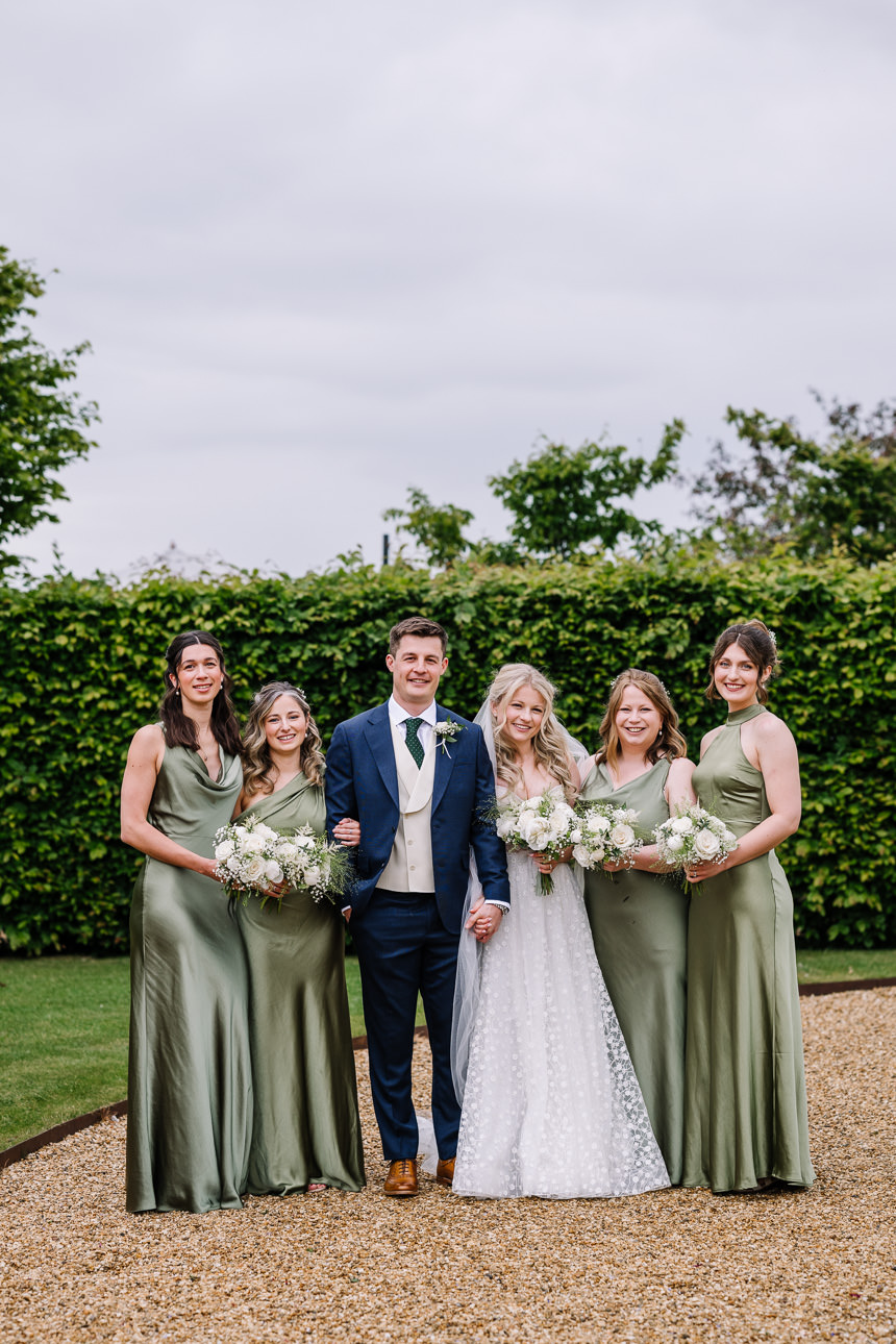 FLORA AND WILLIAM PRIMROSE HILL FARM SPRING WEDDING 39 Bride standing with her bridesmaids outside Primrose Hill Farm on her wedding day