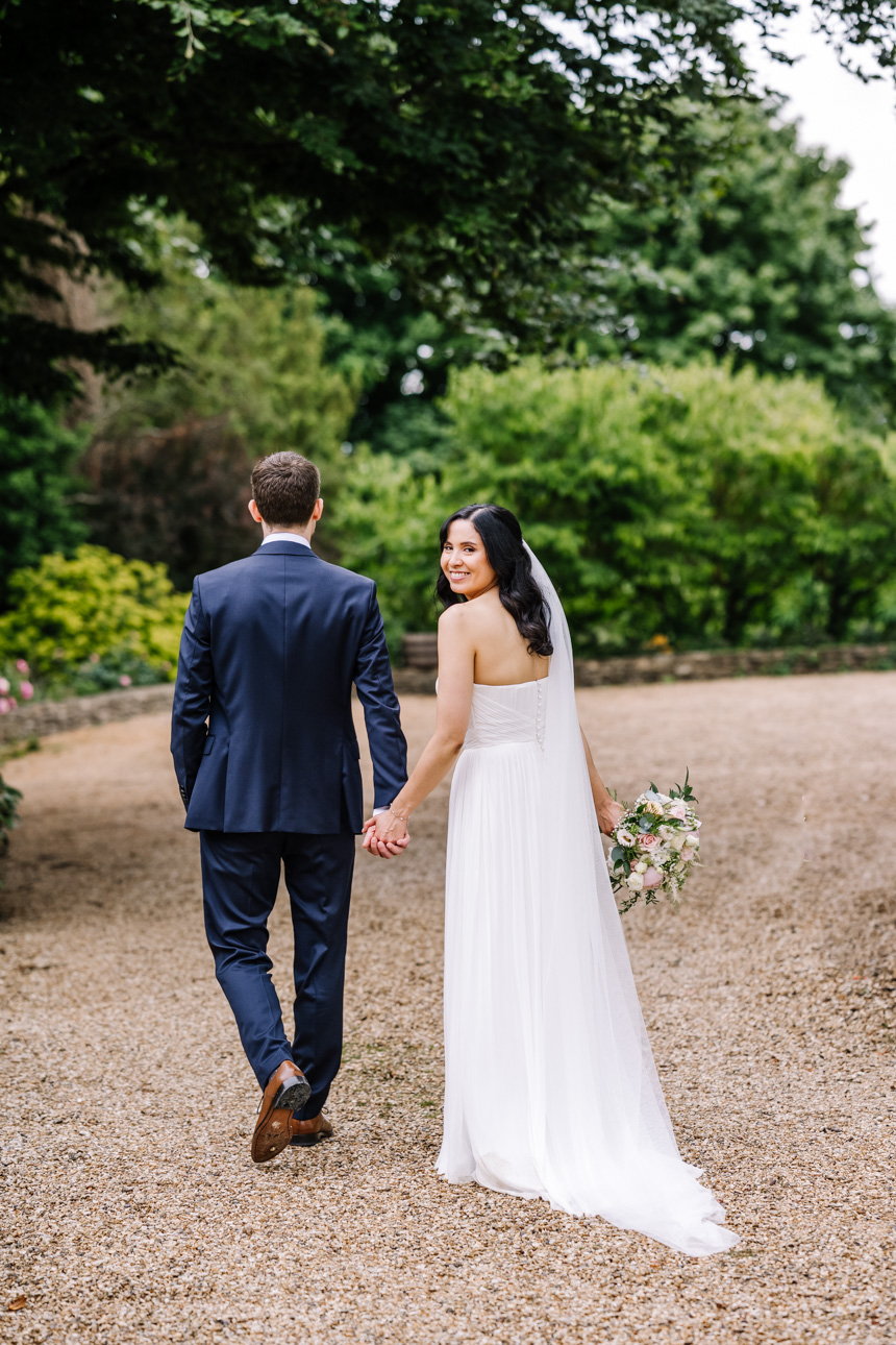 GREAT TYTHE BARN WEDDING PHOTOGRAPHER 53 A newly married couple walking down a scenic tree-lined driveway during their portrait session at The Great Tythe Barn.