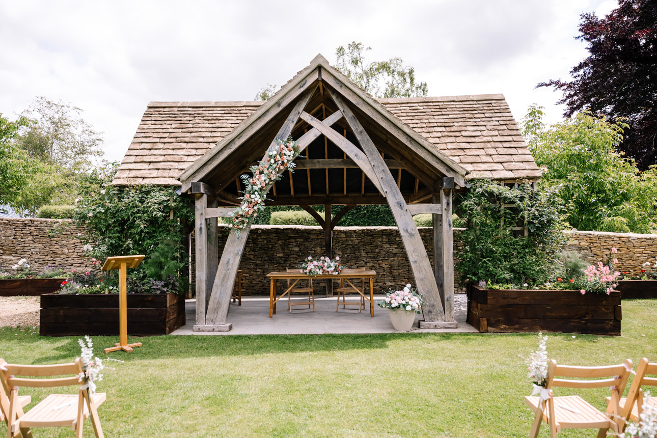 GREAT TYTHE BARN WEDDING PHOTOGRAPHER 37 The traditional, empty Oak Wedding Pavilion altar dressed with rustic greenery and ivory draping at The Great Tythe Barn