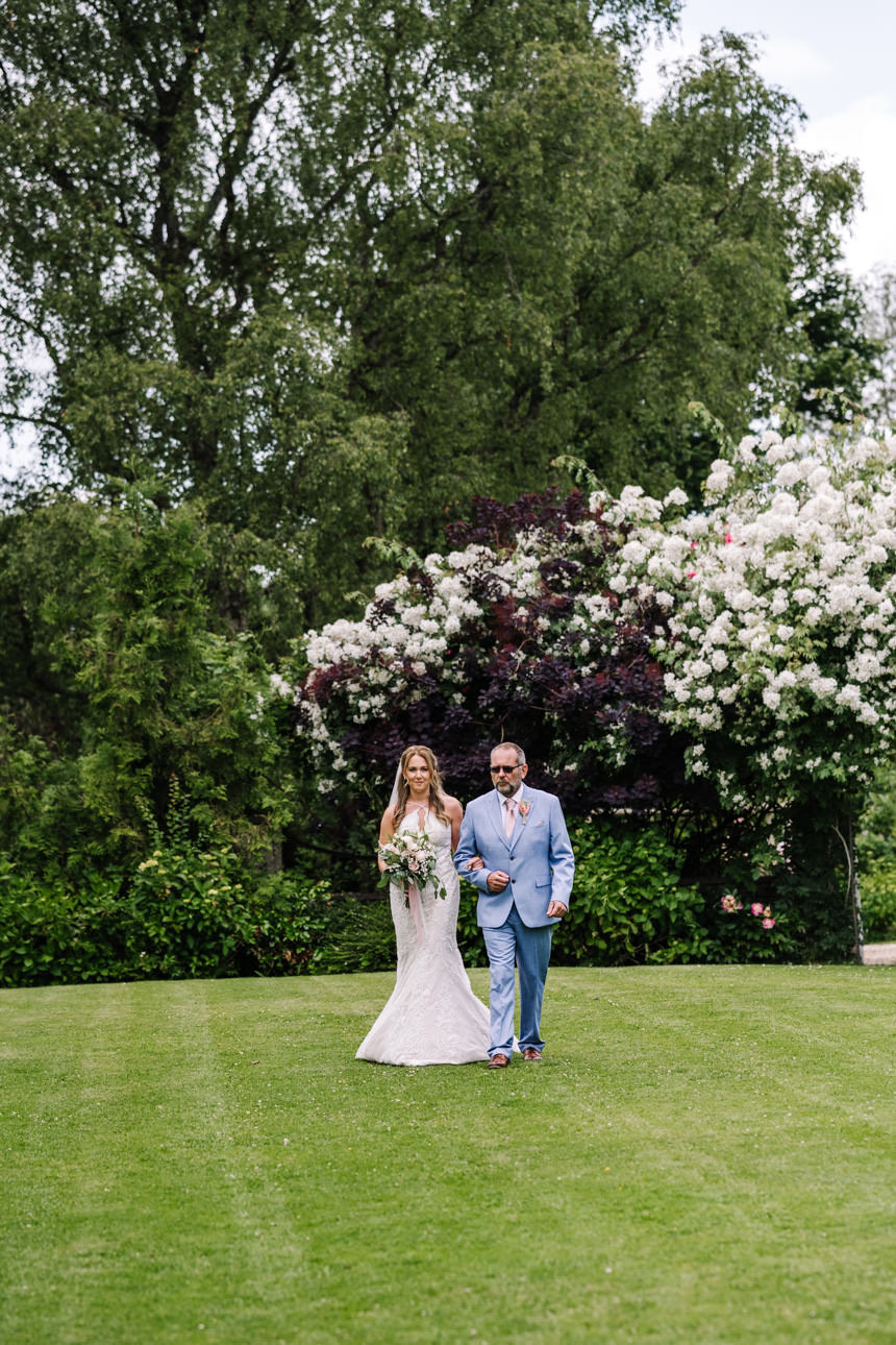 GREAT TYTHE BARN WEDDING PHOTOGRAPHER 40 Bride's entrance at Great Tythe Barn outdoor wedding ceremony