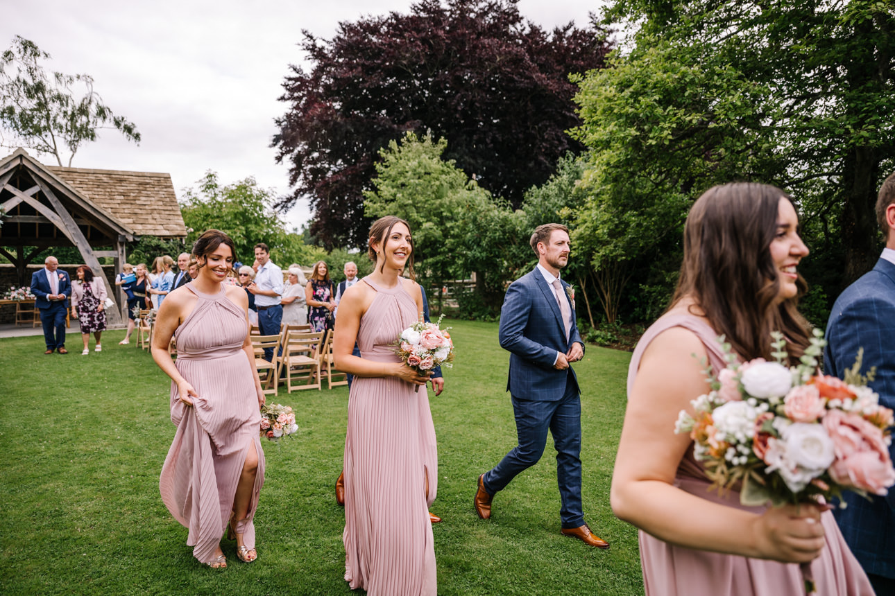 GREAT TYTHE BARN WEDDING PHOTOGRAPHER 44 Wedding guests and bridesmaids chatting and enjoying drinks on the expansive lawns during a summer reception at The Great Tythe Barn.
