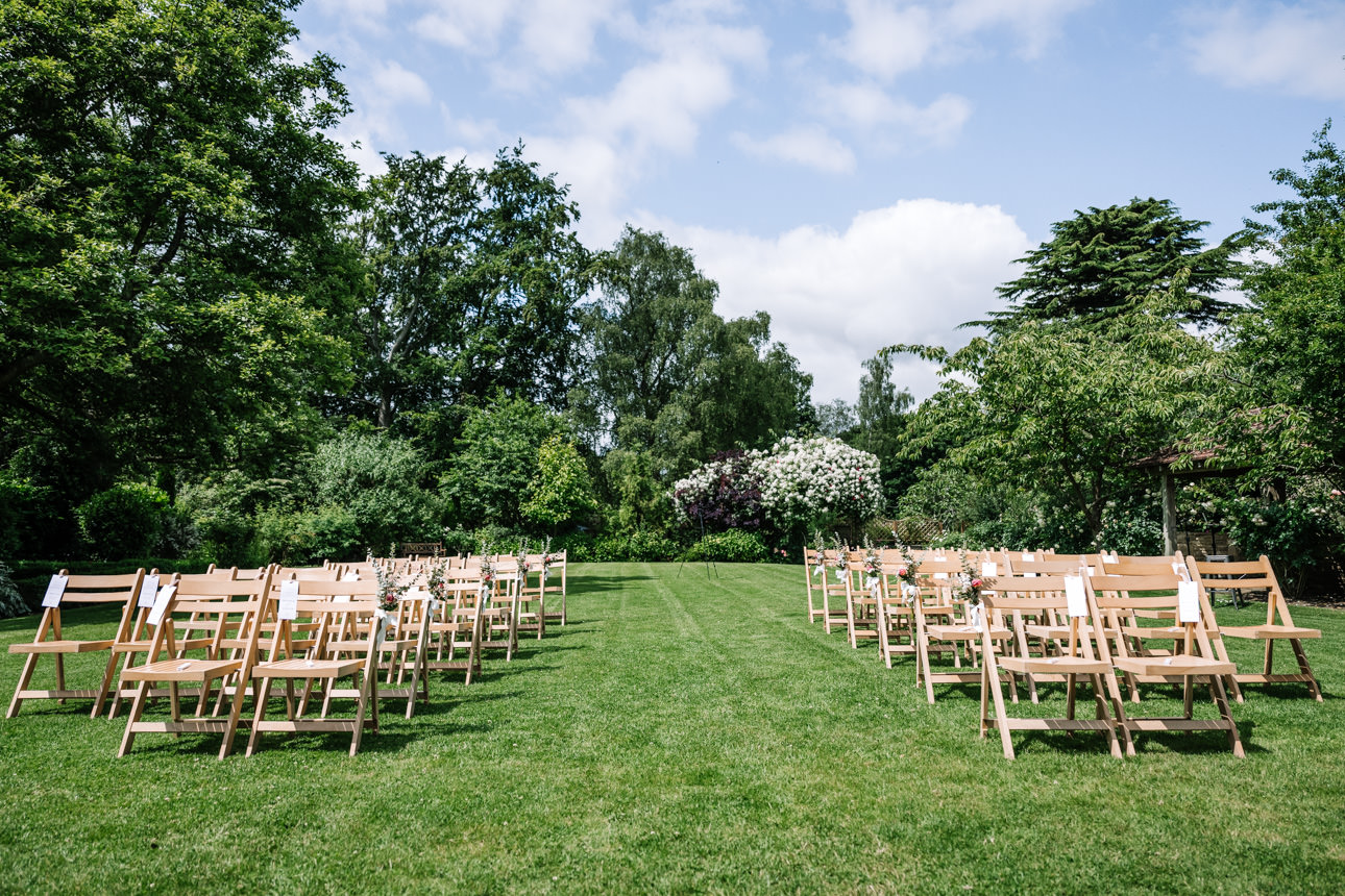 GREAT TYTHE BARN WEDDING PHOTOGRAPHER 35 An empty outdoor ceremony layout showing rows of wooden chairs arranged on the pristine green lawn at The Great Tythe Barn.