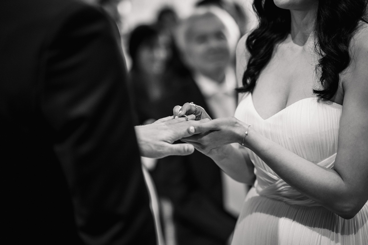 GREAT TYTHE BARN WEDDING PHOTOGRAPHER 26 A close-up black and white photograph of a bride and groom exchanging wedding rings during a ceremony at The Great Tythe Barn.