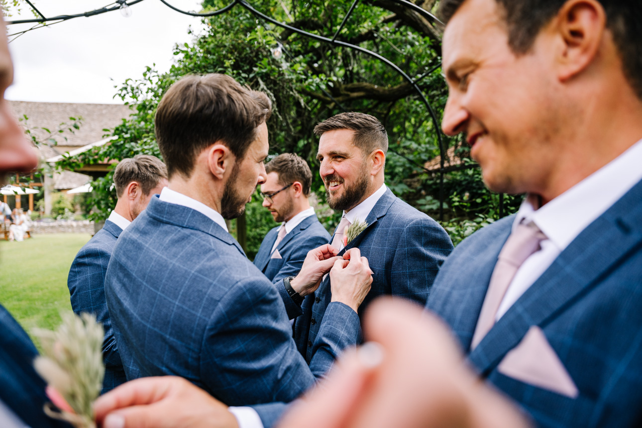 GREAT TYTHE BARN WEDDING PHOTOGRAPHER 21 Great Tythe Barn wedding Photographer capturing groom putting button holes on.